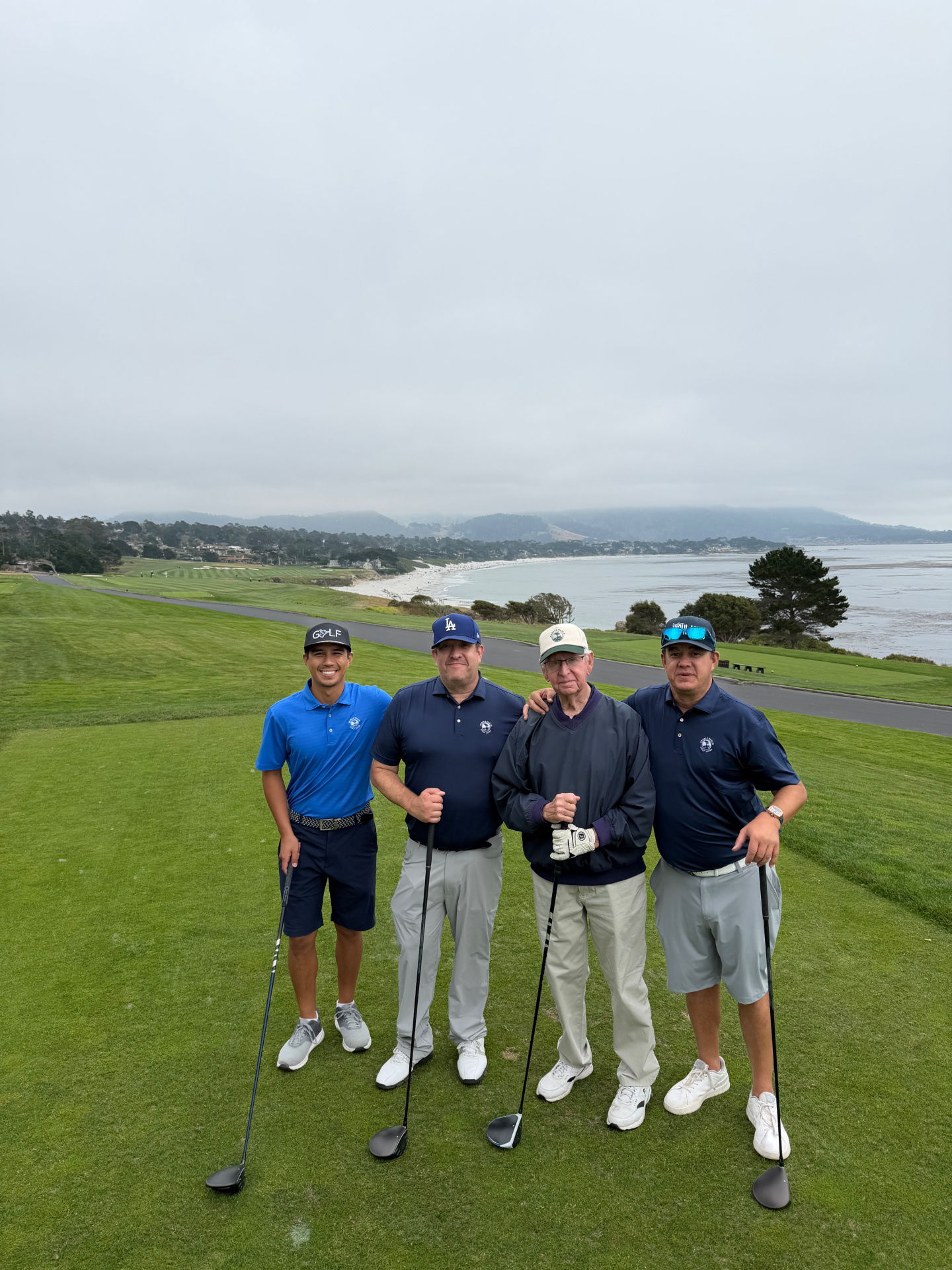 Dave Lennon with his sons and grandson on the tee at Pebble Beach, Carmel Bay behind them